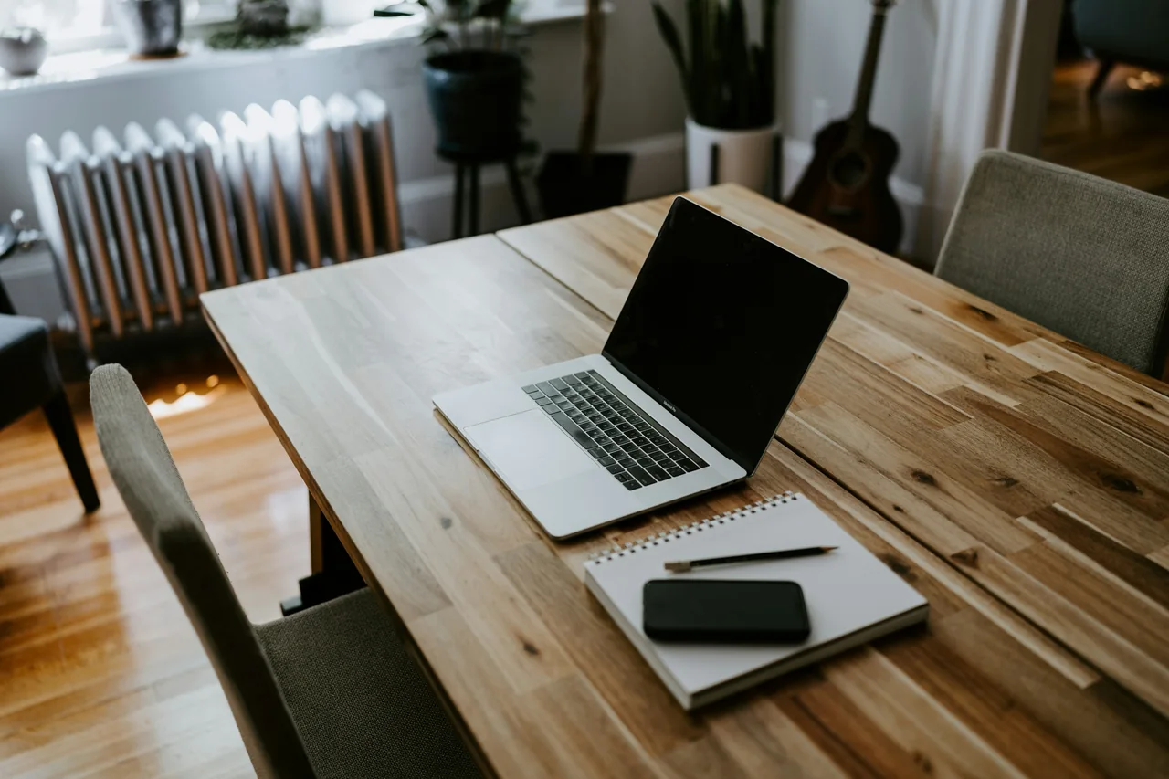 A laptop, notebook and phone at a planning desk